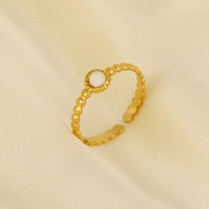 Detail of gold vintage adjustable ring with white bead on beige silk fabric