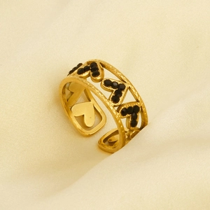 Detail of gold heart-shaped open ring with black crystals on beige satin fabric