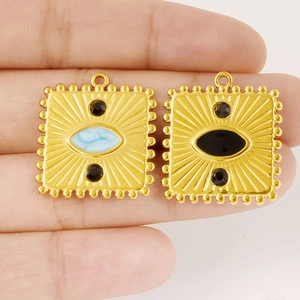 Macro shot of vintage gold evil eye square charms with marble and black stone inlay