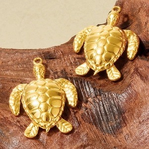 Macro view of gold-plated turtle charms on wood, showing detailed shells and metal texture