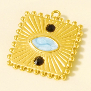 Detailed macro view of a vintage gold pendant with blue enamel eye and black crystals