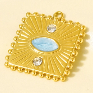 Detail of vintage gold square pendant with sunburst texture, blue enamel eye and zircons