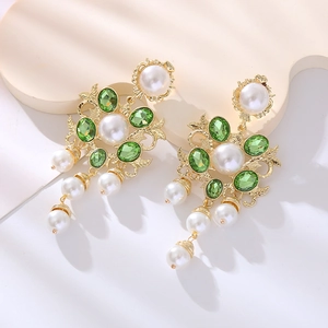 Detail of baroque earrings with green crystals and pearls on gold filigree