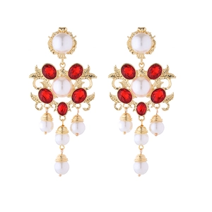 Detail of vintage palace style earrings with red crystals and white pearls on gold metal