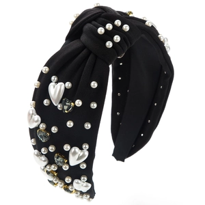 Détail d'un serre-tête noué noir avec perles blanches et strass en forme de cœur gris