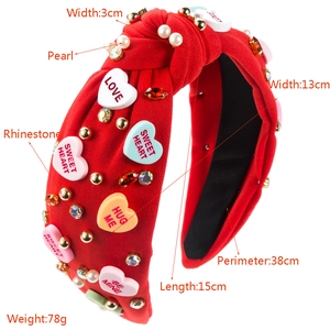 Close-up of red knotted headband with pearls, rhinestones and heart-shaped love charms