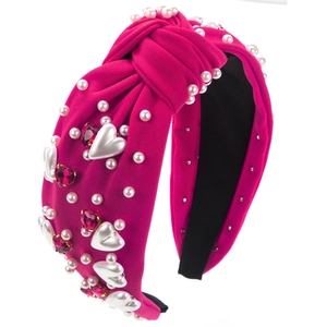 Serre-tête fuchsia avec strass en cœur et perles sur un fond blanc minimaliste