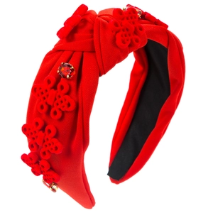 Detail of red fabric headband with knotted knot charms and sparkling red rhinestones