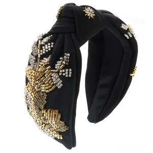 Detail of hand-sewn beads and star rhinestones on a black fabric knotted headband