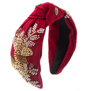 Detailed embroidery of gold beads and sequins on burgundy fabric headband