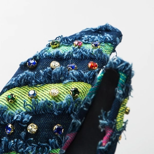 Fashionable denim headband with colorful rhinestones and raw fringe edges on white base