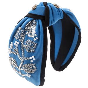 Detail of blue knitted headband with hand-sewn pearl floral patterns and top knot style