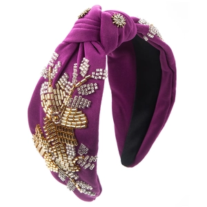 Detail of dark purple fabric headband with handmade golden bead floral patterns