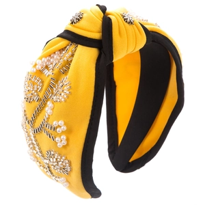 Detailed view of yellow wide knotted headband with hand-sewn pearl flower embroidery