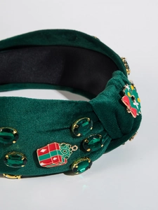 Close-up of green velvet headband with festive enamel charms and emerald gemstones