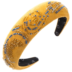 Détail macro du serre-tête rembourré jaune moutarde avec perles bleues et dorées cousues