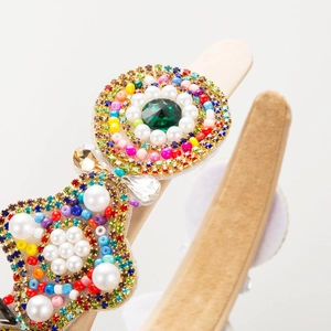 Vintage crystal headband with emerald gemstone and colorful rhinestones on white background