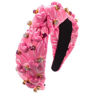 Détail d'un serre-tête rose fleuri orné de charms en cœur et de cristaux en monture dorée