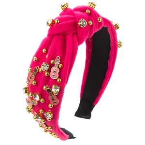 Détail de serre-tête en velours rose fuchsia avec strass et breloque guitare