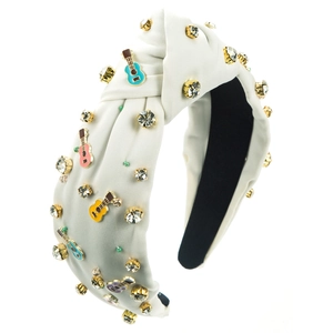 Detail van de witte geknoopte hoofdband met kleurrijke gitaarhangers en fonkelende steentjes