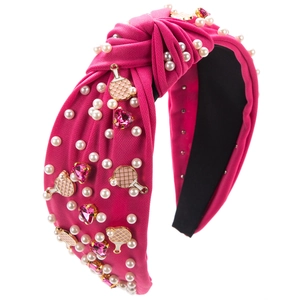 Détail d'un serre-tête noué fuchsia avec perles, cristaux roses et charms de raquette dorés
