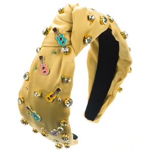 Detail van de champagne satijnen knoop haarband met emaille gitaar en strass