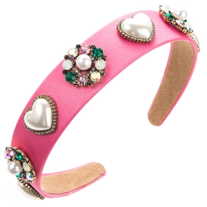 Detail eines rosa Satin-Haarreifs mit Herz-Perlen und bunten Strass-Blumenverzierungen