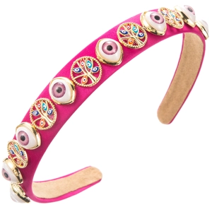 Macro shot of rose red fabric headband featuring golden Evil Eye and resin charms