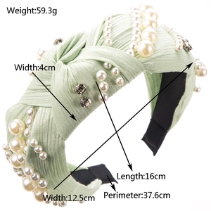 Light green knotted headband with pearls and rhinestones on a white background