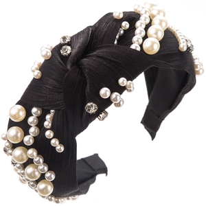 Detail of a black knotted headband featuring elegant pearls and sparkling rhinestones