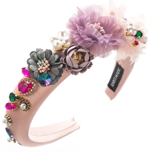 Macro shot of 3D fabric flowers and vibrant rhinestones on a pink handmade headband