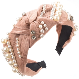 Detailed view of the pleated champagne satin headband with pearls and rhinestones