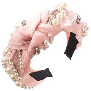 Detail view of a pink knotted headband with elegant pearls and sparkling rhinestones