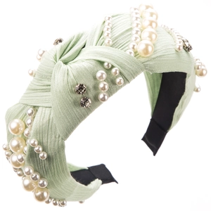 Detailed view of light green pleated headband with faux pearls and dark rhinestones