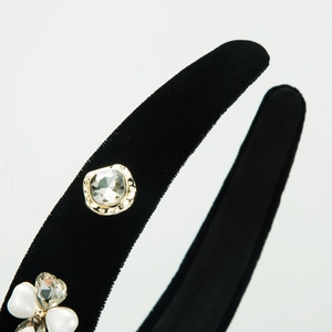 Close-up of black velvet headband with square crystal and pearl clover detailing