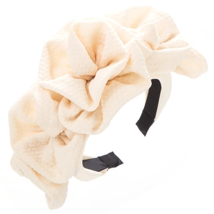 Detailed texture of a cream fabric rose headband with multilayered pleated petals