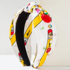 Detalle de diadema temática escolar con lápices amarillos, manzana y emblema Lucky