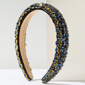 Baroque padded headband with deep blue rhinestones on a white geometric stand