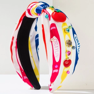 Detalle de la diadema de tela estampada con adornos de manzana y pedrería de lujo