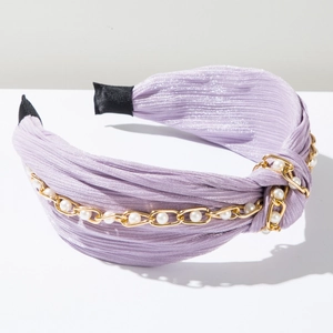 Detailstruktur des lila plissierten Haarreifs mit goldener Kette und weißen Perlen