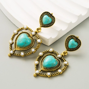 Detail of vintage heart earrings with turquoise stones and golden braided textures