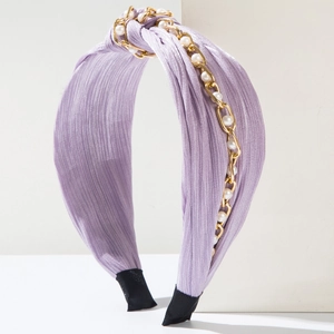 Detail eines fliederfarbenen Knotenstirnbands mit Goldkette und Perlenakzenten