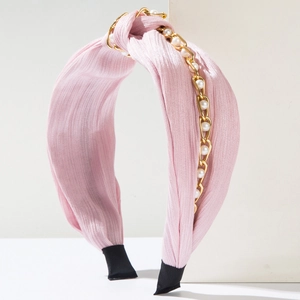 Detail eines rosa Stoffstirnbands mit goldener Kette und weißen Perlen für Damen