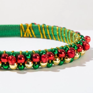 Close-up of green velvet headband with red, green, and gold bells tied with gold wire