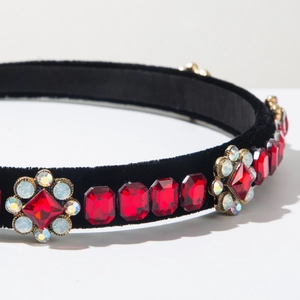 Detailed macro shot of vintage velvet headband with red crystals and rhinestone flowers