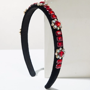 Detailed macro view of black velvet headband with red crystals and floral gemstone patterns