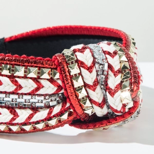 Close-up of red knotted headband with metallic fabric, braided rope and sparkling rhinestones