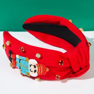 Détail d'un serre-tête rouge avec un casse-noisette perlé et des strass étincelants