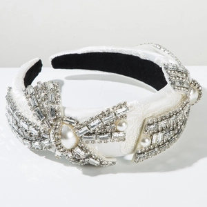 Dettaglio ravvicinato di un cerchietto bianco con strass argentati e fiocco di perle
