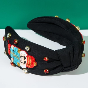Détail du motif casse-noisette perlé et strass rouges sur serre-tête noir noué